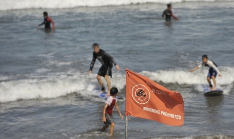   Sejumlah wisatawan berselancar di pantai meski telah dipasangi bendera larangan berenang terkait kewaspadaan dampak Tsunami Chili, di Pantai Kuta, Bali, Kamis (3/4). (Antara/Nyoman Budhiana)