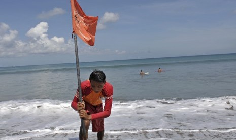  Petugas Badan Penyelamat Wisata Tirtha (Balawista) Kabupaten Badung memasang bendera rambu-rambu larangan berenang menyusul adanya seruan kewaspadaan dampak Tsunami Chili, di Pantai Kuta, Bali, Kamis (3/4). (Antara/Nyoman Budhiana)