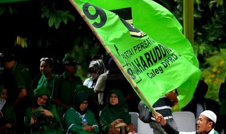 Simpatisan mengibarkan bendera Partai Persatuan Pembangunan (PPP) saat kampanye PPP Tugu Proklamasi, Jakarta Pusat, Sabtu (5/4). (Republika/Prayogi)