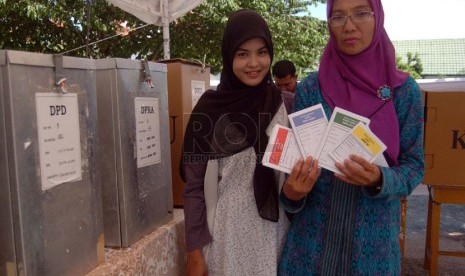  Dua orang wanita memperlihatkan kertas suara yang dipilihnya untuk dimasukan ke dalam kotak suara di TPS kawasan Blang Cut, Banda Aceh, Nanggroe Aceh Darussalam (NAD), Rabu (9/4). (Republika/Rusdy Nurdiansyah)