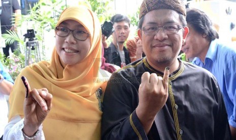 Gubernur Jabar, Ahmad Heryawan bersama istri memperlihatkan tanda tinta di kelingking usai melakukan pencoblosan di TPS 1 Keluarahan Babakan Ciamis, Bandung, Rabu (9/4). (Republika/Edi Yusuf)