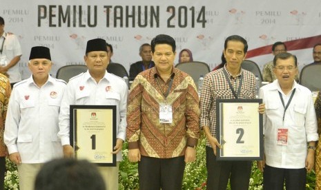  Pasangan capres dan cawapres Prabowo Subianto-Hatta Rajasa (kiri) dan Joko Widodo-Jusuf Kalla (kanan) diapit Ketua KPU Husni Kamil Manik (tengah), saat pengundian nomor urut Pilpres 2014 di Gedung KPU, Jakarta, Ahad (1/6). (Republika/Agung Supriyanto)