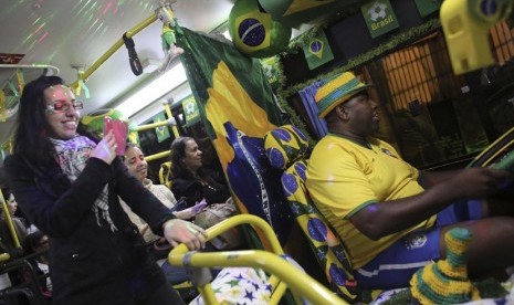   Sopir bus Edilson (kanan) mengenakan jersey timnas Brasil saat ia mengendarai sebuah bus kota yang dihiasi dengan warna bendera Brasil dan motif Piala Dunia 2014 di Santo Andre, pinggiran kota Sao Paulo, Rabu (18/6). (REUTERS/Nacho Doce)