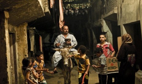  Seorang pria yang mengendarai keledai membangunkan warga untuk sahur di Kairo, Mesir, Senin (30/6).   (AP/ Mohammed Abu Zaid)