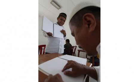  Guru mengaji Khairil Anwar (kiri) mengajarkan bacaan ayat suci Al Quran kepada para tuna netra dengan menggunakan huruf braille saat menggelar tadarusan di Medan, Sumut, Kamis (3/7).    (Antara/Septianda Perdana)