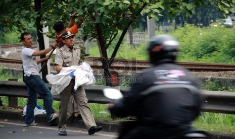 Petugas Satpol PP melepas atribut kampanye yang terpasang di Jalan Tentara Pelajar, Jakarta, Ahad (6/7). (Republika/Yasin Habibi)