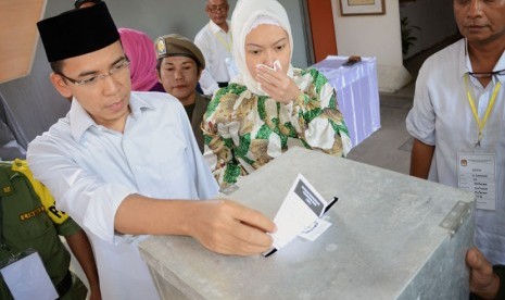 Gubernur NTB M Zainul Majdi (kiri) beserta isteri Erika Zainul Majdi (kanan) memasukkan surat suara usai mencoblos di TPS 1 Lingkungan Pusaka, Mataram, NTB, Rabu (9/7).(Antara/Ahmad Subaidi)