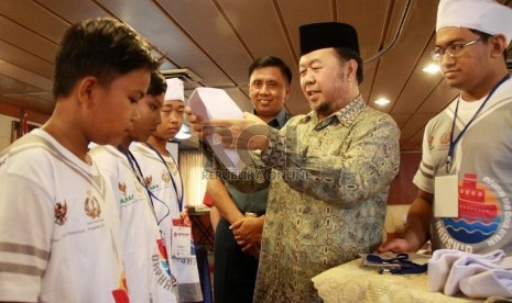  Ketua Umum Baznas KH. Didin Hafidhuddin (kedua kanan) memasangkan peci kepada peserta pesantren kilat Orpanship disaksikan Kepala staf Kolinlamil Laksamana Pertama Karma Suta (tengah) di  Jakarta, Kamis (17/7). (Republika/ Yasin Habibi)