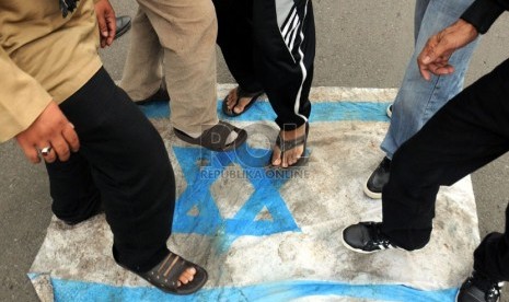   Pengunjuk rasa menginjak bendera Israel saat berdemonstrasi di Jalan MH Thamrin, Jakarta, Jumat (25/7). (Republika/Aditya Pradana Putra)