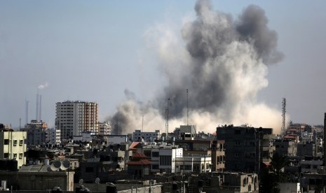  Asap mengepul dari bangunan di utara kota Gaza, Jumat (8/8), akibat serangan pertama militer Israel sejak  gencatan senjata selama tiga hari.  (EPA/Mohammed Saber)