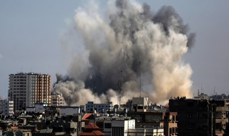  Asap mengepul dari bangunan di utara kota Gaza, Jumat (8/8), akibat serangan pertama militer Israel sejak  gencatan senjata selama tiga hari.  (EPA/Mohammed Saber)