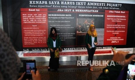 Mahasiswa berfoto sekuritas dengan latar belakang sosialisasi Tax Amnesty saat digelar pameran sekuritas di Bursa Efek Indonesia (BEI), Jakarta, Kamis (21/7).