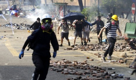 Mahasiswa demonstran berlarian saat polisi menembakkan gas air mata di kampus Hong Kong Polytechnic University di Hong Kong, Senin (18/11). 