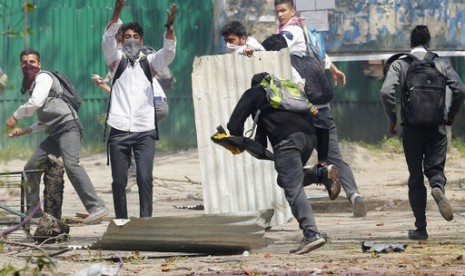 Mahasiswa Kashmir berlari mencari perlindungan saat polisi India menembakkan peluru karet dan gas air mata untuk membubarkan bentrokan di Srinagar, Kashmir yang dikuasai India, 17 April 2017. 