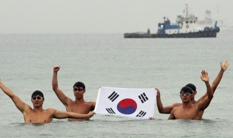 Mahasiswa Korea Selatan mengibarkan bendera Korea Selatan di  pelabuhan timur Ujin, Korea Selatan sebelum melakukan renang estafet ke Kepulauan Dokdo yang menjadi sengketa antara Korea Selatan dan Jepang. 