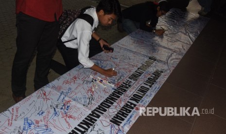 Mahasiswa membawa karangan bunga yang berisi dukungan kepada mahasiswa berkebutuhan khusus korban bullying berinisial MF di depan gedung rektorat Kampus Gunadarma, Depok, Jawa Barat, Senin (17/7). 