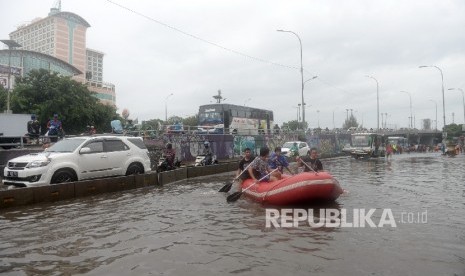 Mahasiswa Universitas Tarumanegara menggunakan perahu karet saat banjir di kawasan Grogol, Jakarta Barat, Selasa (21/2).