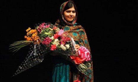 Malala Yousafzai poses with a bouquet after speaking during a media conference at the Library of Birmingham, in Birmingham, England, Friday, Oct. 10, 2014, after she was named as winner of The Nobel Peace Prize. 