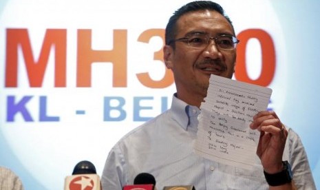 Malaysia's acting Transport Minister Hishammuddin Hussein holds up a note that he has just received on a new lead in the search for the missing Malaysia Airlines Flight MH370, during a news conference at Kuala Lumpur International Airport March 22, 2014. 