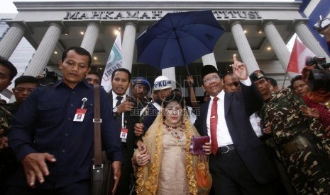   Mantan Ketua Mahkamah Konstitusi Mahfud MD bersama istri memberikan salam perpisahan kepada para pendukungya di Gedung MK, Jakarta, Senin (1/4). (Republika/Adhi Wicaksono)