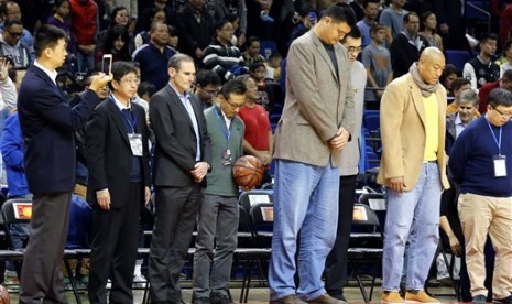 Mantan pemain basket NBA Yao Ming (paling tinggi) mengheningkan cipta di dalam perlombaan persahabatan antara dua kampus di Shanghai, Cina, (14/11). Simpati atas teror Paris dilakukan di hampir seluruh belahan dunia.