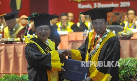 Mantan Wakil Presiden Jusuf Kalla (kiri) berjabat tangan dengan Rektor Universitas Negeri Padang (UNP) Ganefri (kanan) saat penganugerahan gelar doktor kehormatan (Dr. Honoris Causa), di kampus tersebut di Padang, Sumatera Barat, Kamis (5/12/2019).