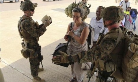 Marines and sailors with Special-Purpose Marine Air-Ground Task Force Crisis Response help US  citizens into a Marine Corps KC-130J Hercules airplane during an evacuation of personnel from the US Embassy, in Juba, South Sudan, January 3, 2014, 