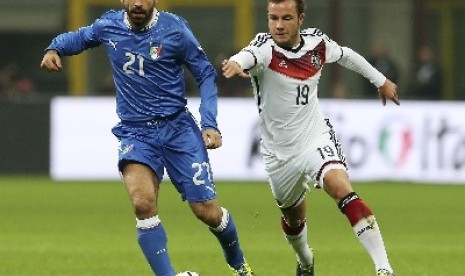 Mario Goetze (kiri) berebut bola dengan Andrea Pirlo.