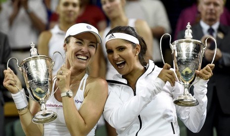 Martina Hingis (L) of Switzerland and Sania Mirza of India celebrate with their trophies after winning against Ekaterina Makarova and Elena Vesnina of Russia during their Women's doubles final match for the Wimbledon Championships at the All England Lawn T