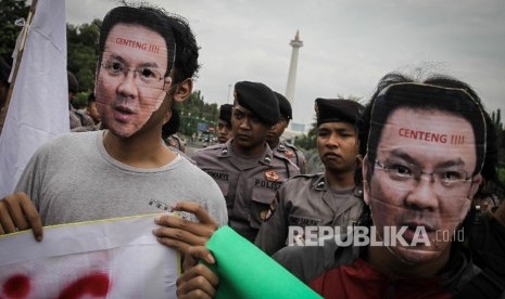 Masa yang tergabung dalam Aliansi Pro Demokrasi memakai topeng Gubernur Provinsi DKI Jakarta Basuki Tjahaja Purnama saat melakukan aksi di Silang Monas, Jakarta, Jumat (30/9).