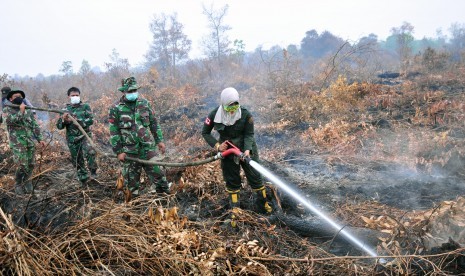 Masitoh (kanan) seorang perempuan anggota pemadam kebakaran Manggala Agni bersama beberapa personel TNI melakukan pemadaman kebakaran di lahan gambut di Rimbo Panjang Kabupaten Kampar, Riau, Rabu (9/9).