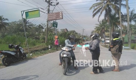 Masker dibagikan ke pengendara yang mengarah ke sekitaran kaki-kaki Gunung Merapi, Jum'at (11/5).  Pengendara turut diminta menjauhi akses jalan radius 3-5 kilometer dari puncak Gunung Merapi.