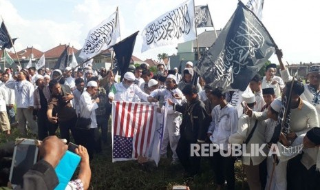 Massa aksi bela Palestina membakar replika bendera Amerika Serikat dan bendera Israel di sekitaran kantor Konsulat Jenderal Amerika Serikat Surabaya Jalan Citra Niaga, Sambikerep, Surabaya, Jumat (15/12). 