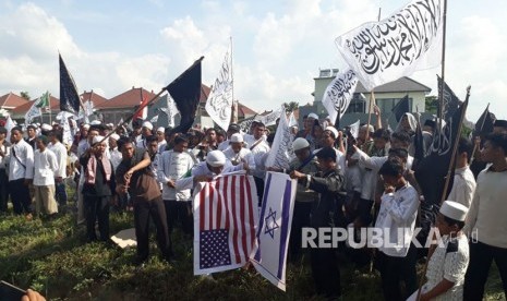 Massa aksi bela Palestina membakar replika bendera Amerika Serikat dan bendera Israel di sekitaran kantor Konsulat Jenderal Amerika Serikat Surabaya Jalan Citra Niaga, Sambikerep, Surabaya, Jumat (15/12).