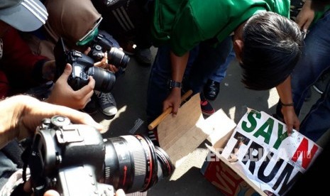 Massa aksi damai darurat Yerusalem membakar kardus dengan kertas bertuliskan Say No To Trump sebagai ganti ban yang sebelumnya dipadamkan oleh kepolisian di depan gedung Kedutaan Besar Amerika Serikat, Jumat (8/12). 