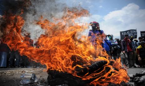 Massa aksi yang tergabung dari buruh dan mahasiswa membakar ban saat melakukan aksi blokir jalan nasional Bandung-Garut-Tasikmalaya menuju Gerbang Tol Cileunyi di Cileunyi, Kabupaten Bandung, Jawa Barat, Kamis (8/10/2020). Aksi tersebut merupakan penolakan buruh dan mahasiswa terhadap pengesahan UU Cipta Kerja yang telah disahkan oleh DPR.