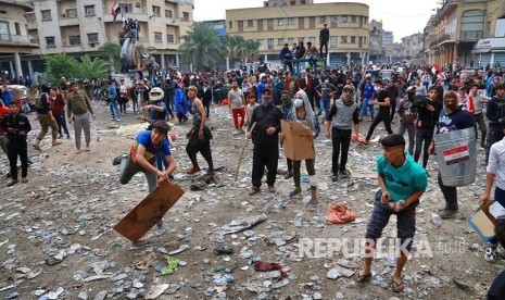 Massa anti pemerintah melemparkan batu ke arah petugas keamanan dalam unjukrasa di Baghdad, Irak, Kamis (28/11).