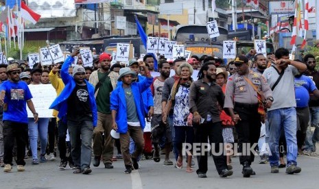 Massa berjalan kaki menuju Kantor Gubernur Papua saat melakukan aksi di Jayapura, Senin (19/8). Aksi tersebut untuk menyikapi peristiwa yang dialami mahasiswa asal Papua di Surabaya, Malang dan Semarang.