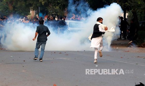 Massa berunjukrasa penentang Revisi UU Kewarganegaraan baru melarikan diri dari tembakan gas air mata polisi India di New Delhi, India, Ahad (15/12). Saat ini India sedang dilanda aksi demonstrasi memprotes UU kewarganegaraan.