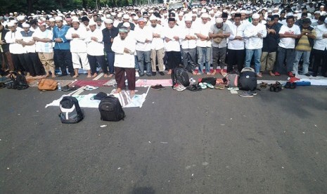 Massa demonstran gelar shalat Ashar di Jalan Merdeka Selatan, Jakarta Pusat, depan Balai Kota DKI Jakarta,  Jumat (4/11).