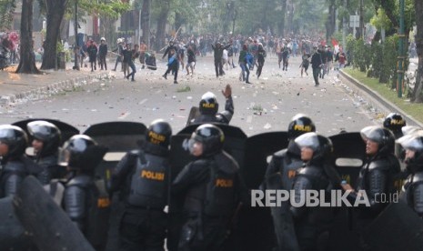 Massa melemparkan batu ke arah barisan polisi saat unjuk rasa menolak UU KPK hasil revisi dan RUU KUHP, di kawasan Titik Nol Kota Medan, Sumatera Utara, Jumat (27/9/2019).