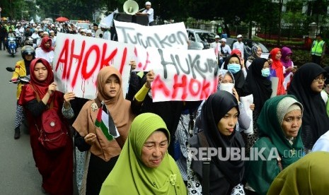 Massa membentangkan poster di depan Gedung Sate, Kota Bandung, pada aksi demonstrasi umat Islam terkait pernyataan kontoversi Gubernur DKI Jakarta, Basuki Tjahaja Purnama atau Ahok yang mengutip salah satu ayat Alquran, Jumat (21/10).