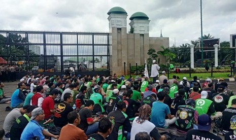 Massa Ojek Daring menggelar salat Jumat berjamaah di depan Gerbang Kompleks Parlemen RI, Jalan Gatot Subroto, Jakarta, Jumat (28/2). 