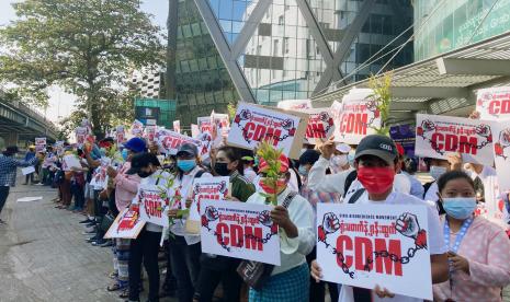 Massa pengunjuk rasa anti-kudeta memegang poster bertuliskan CDM, singkatan dari Gerakan Pembangkangan Sipil, saat mereka berkumpul di luar Hledan Center di Yangon, Myanmar, Minggu, 14 Februari 2021. Demonstrasi jalanan massal harian di Myanmar sedang berlangsung minggu kedua mereka, dengan baik pengunjuk rasa maupun pemerintah militer mereka berusaha untuk turun dari kursi yang menunjukkan tanda-tanda mundur dari konfrontasi. 