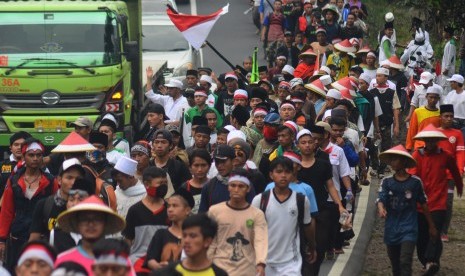 Massa yang tergabung dalam Gerakan Nasional Pengawal Fatwa Majelis Ulama Indonesia (GNPF-MUI) berjalan kaki menuju Jakarta di Jalan Raya Tasikmalaya-Malangbong, Kampung Cipeudeuy, Kabupaten Garut, Jawa Barat, Selasa (29/11). 