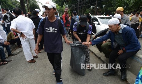 Massa yang tergabung dalam GNPF MUI memungut sampah saat melakukan aksi kawal sidang ahok.