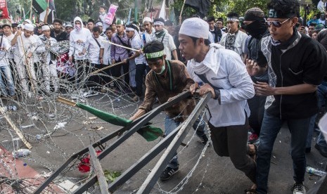 Massa yang tergabung dalam Himpunan Mahasiswa Islam merusak kawat berduri saat unjuk rasa  4 November di Jakarta, Jumat (4/11). 