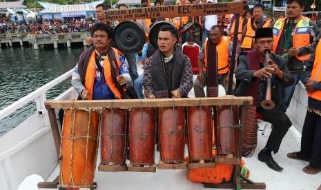  Masyarakat adat Batak memainkan alat musik Gondang ketika melaksanakan ritual di atas kapal motor, di Danau Toba, Simalungun, Sumatera Utara, Sabtu (23/6).