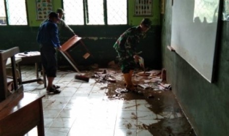 Masyarakat bersama babinsa Dayeuhkolot tengah membersihkan sisa lumpur  akibat banjir di SDN 01 Bojong Asih, Dayeuhkolot, Kabupaten Bandung, Rabu  (27/2).