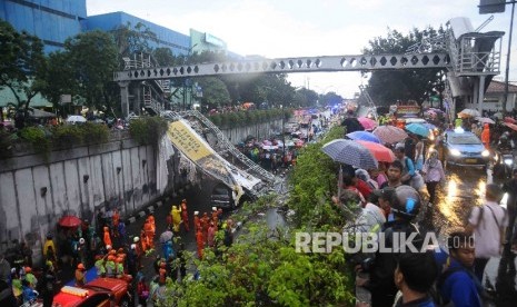 Masyrakat menonton proses evakuasi reruntuhan papan reklame yang roboh dari sebuah JPO di Pasar Minggu, Jakarta Selatan, Sabtu (24/9).